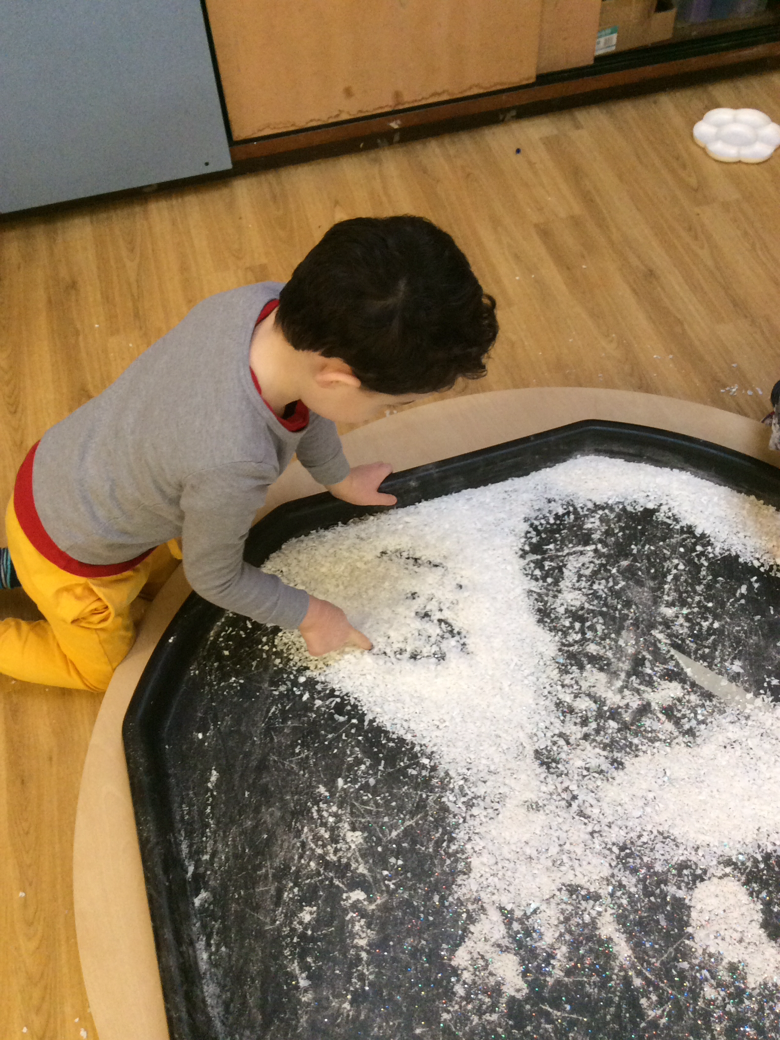 young boy on knees playing in sand